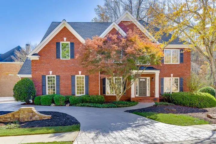 Traditional brick facade home featuring a gabled roofline and dark shutters