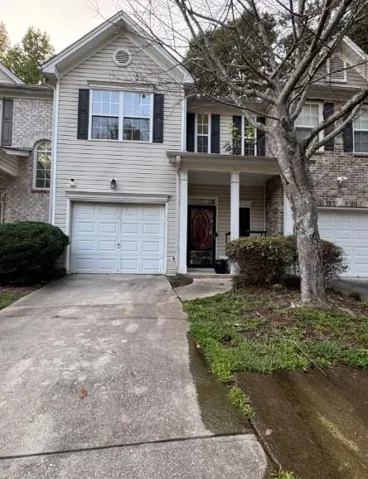 Vinyl siding exterior with a prominent front door, white garage door, and decorative window shutters