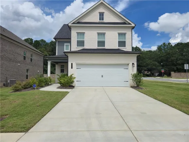 Two-story residence featuring light-colored brick and siding, a two-car garage, and a concrete driveway