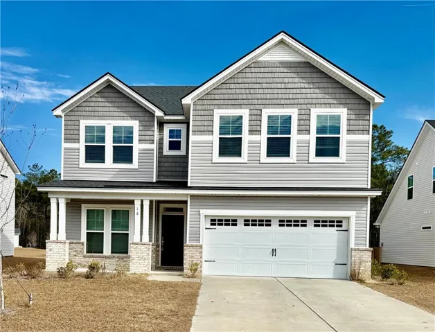 Craftsman-style house with a porch, driveway, brick siding, and an attached garage