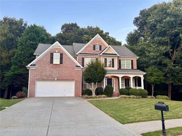 Brick and siding exterior with gabled roof lines, an attached two-car garage, and a covered front porch with white columns