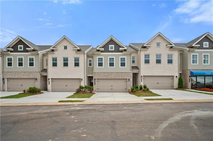 Contemporary townhome exteriors featuring light-colored brick, horizontal siding, gabled rooflines, and individual garages