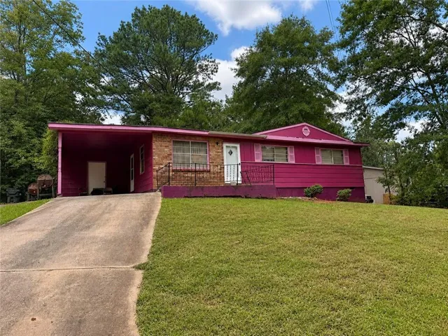 Brick and siding exterior with a carport, featuring a sloped front lawn and established trees