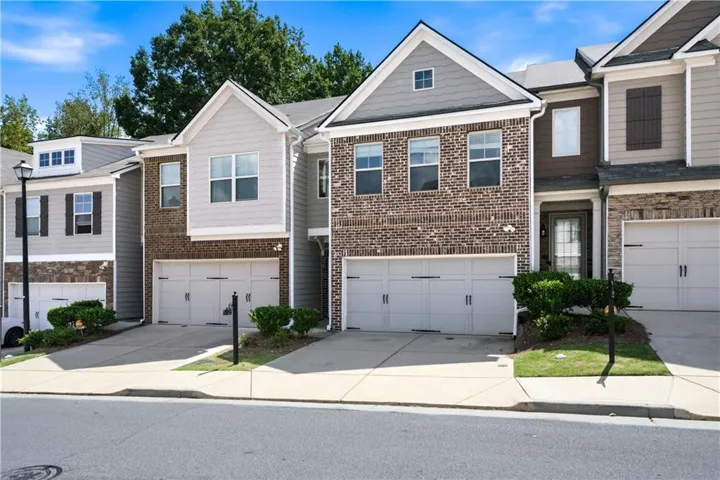 Townhome exterior featuring brick and siding facade, covered entry, and attached two-car garage