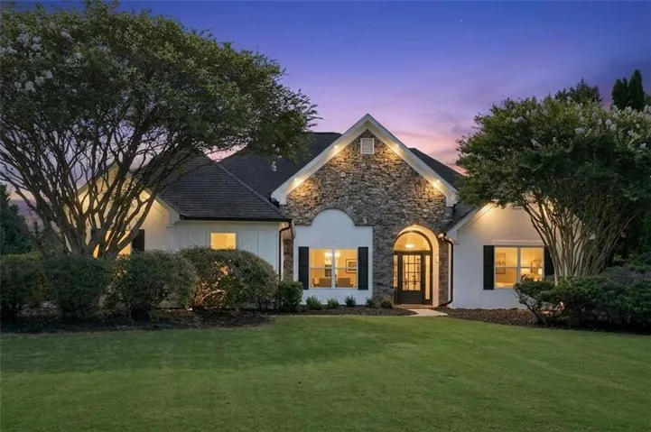 Stone and stucco exterior with a dark shingle roof