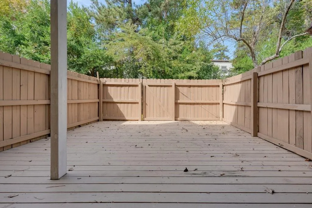 NOT STAGED private fenced patio featuring wood decking and a gated entrance
