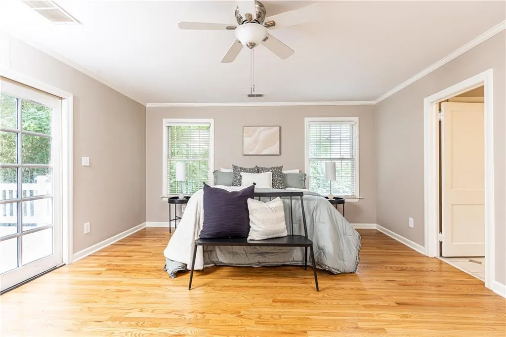 Bedroom featuring light wood-type flooring, ornamental molding, and a ceiling fan