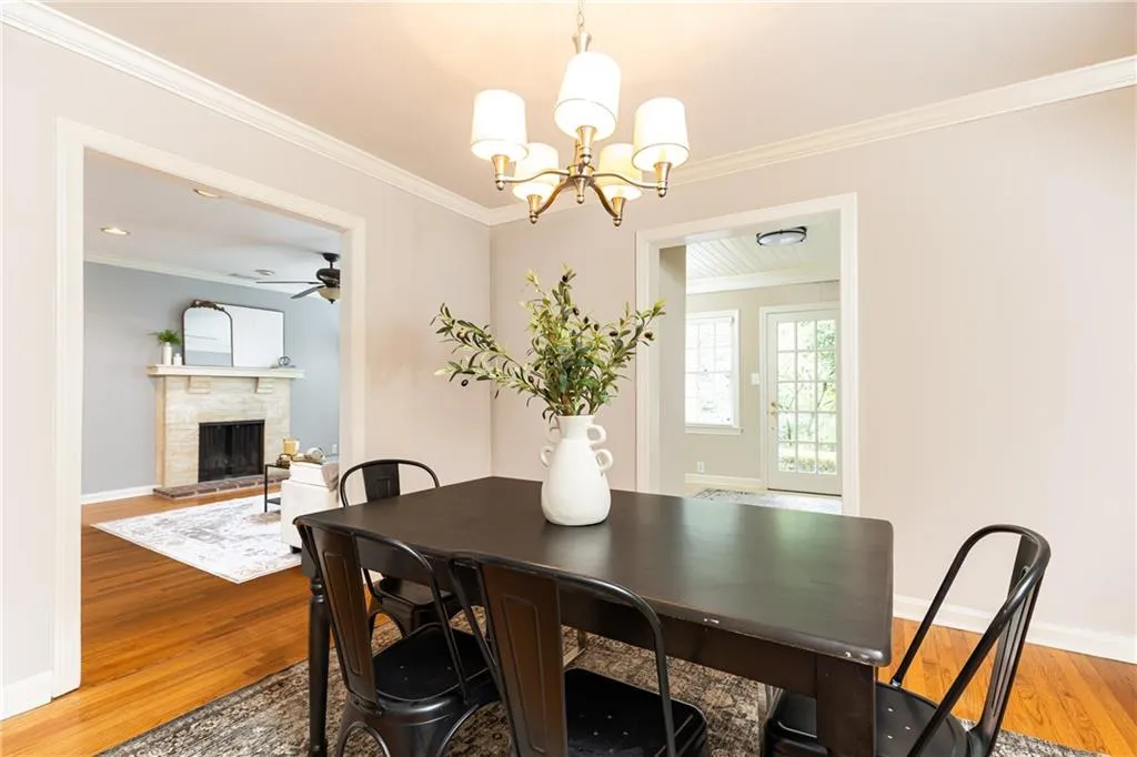 Dining room featuring ornamental molding, light wood-style floors, a fireplace, a ceiling fan, and a chandelier