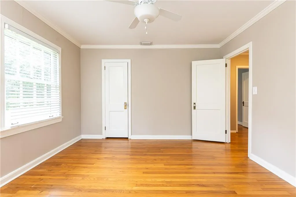 Unfurnished bedroom with light wood-style flooring, crown molding, and a ceiling fan