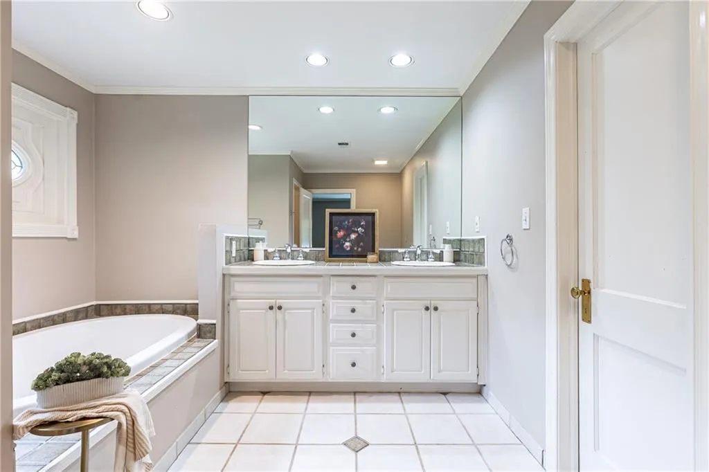 Full bathroom featuring crown molding, double vanity, tile patterned floors, a garden tub, and recessed lighting