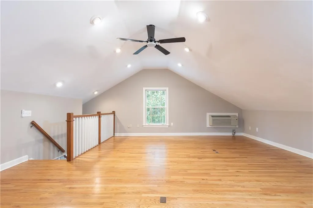 Additional living space with light wood finished floors, lofted ceiling, a wall mounted air conditioner, recessed lighting, and ceiling fan