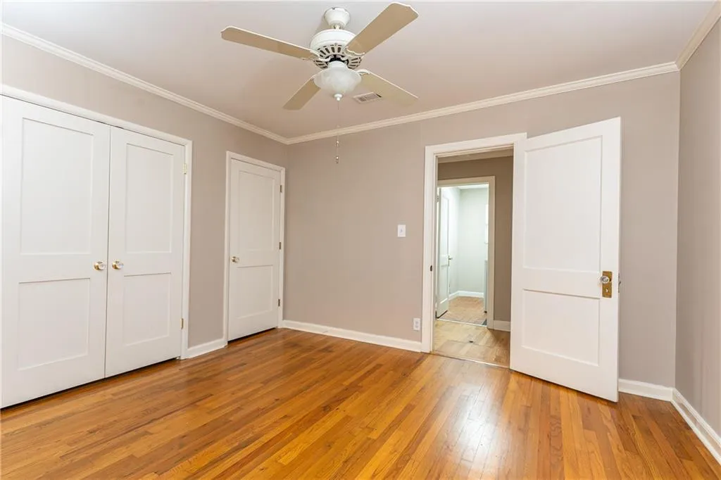 Unfurnished bedroom with light wood-style floors, crown molding, a ceiling fan, and a closet