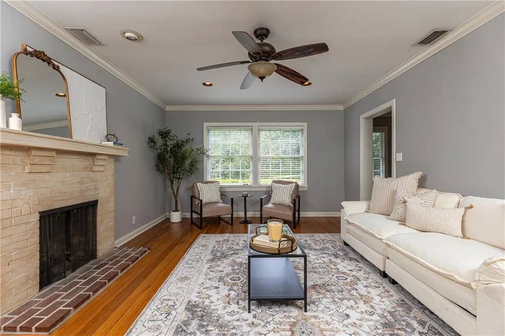 Living room featuring crown molding, ceiling fan, wood finished floors, a fireplace, and recessed lighting
