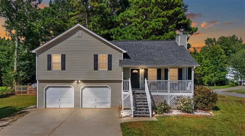 Exterior featuring gray siding, a covered front porch with white railings, a two-car garage, and a concrete driveway