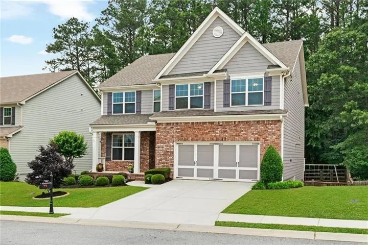 Two-story home with a brick and siding exterior, a two-car garage, and a covered front porch