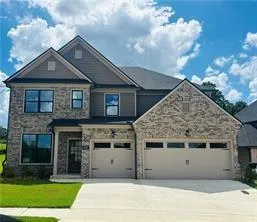 Two-story exterior featuring a partial stone facade, partial siding, and a gabled roofline