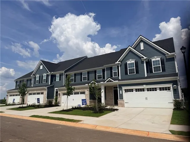 Townhome exterior featuring blue siding, white trim, stone accents, two-car garage, and dark shingle roof