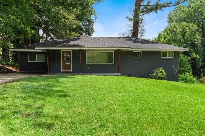 Ranch-style exterior featuring a dark gray facade, a brown front door with glass inserts, and a dark shingle roof