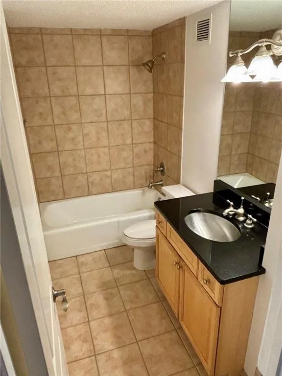 Full bathroom with tile patterned floors, vanity, a textured ceiling, and shower / tub combination