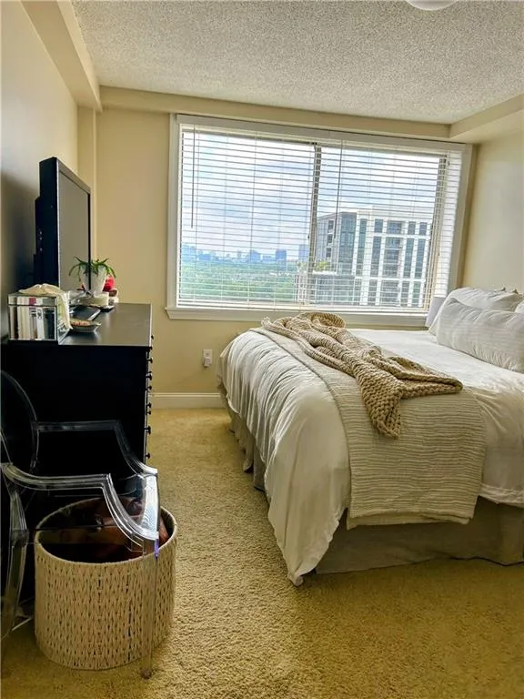 Bedroom featuring light colored carpet and a textured ceiling