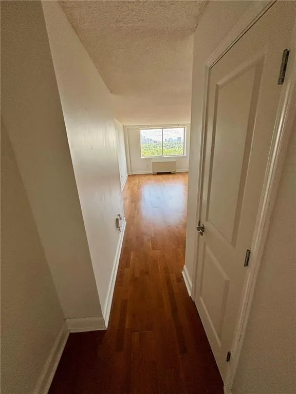 Hallway featuring a textured ceiling and wood finished floors