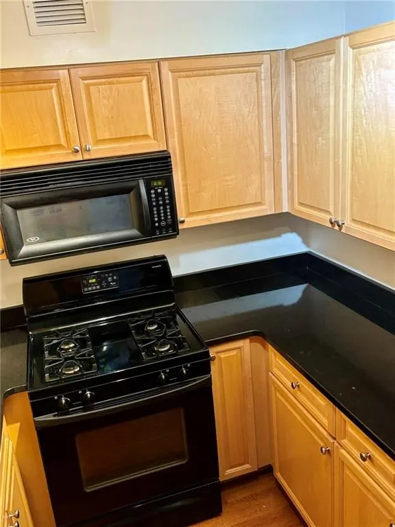 Kitchen featuring black appliances, dark countertops, and wood finished floors