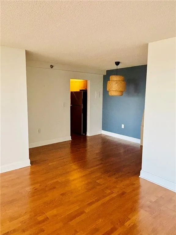Unfurnished room with a textured ceiling and wood finished floors