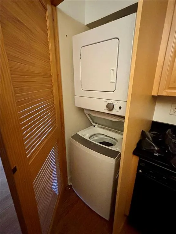 Laundry room with stacked washer / dryer and dark wood finished floors