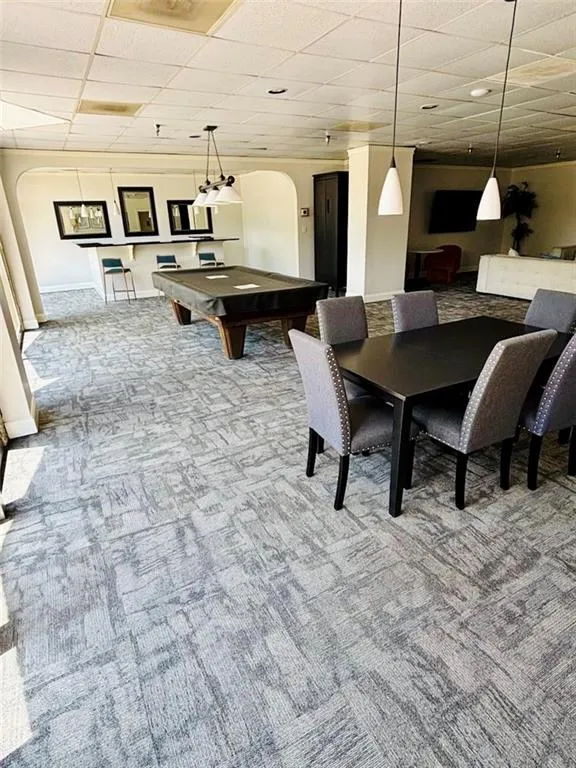 Playroom with arched walkways, pool table, carpet floors, and a drop ceiling