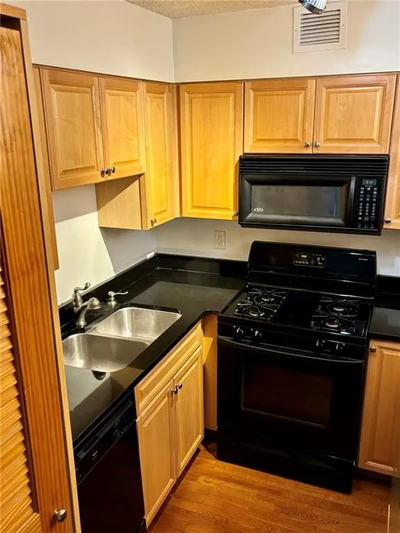 Kitchen with black appliances, dark countertops, dark wood-style floors, and a textured ceiling