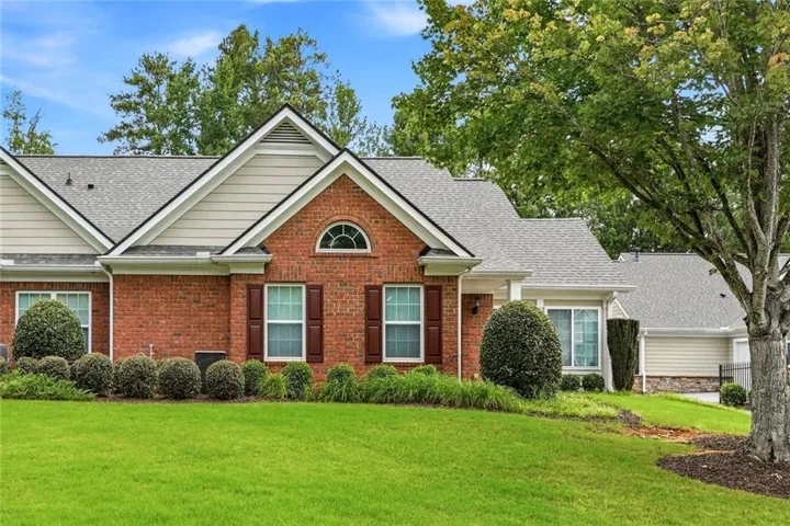 Brick facade with beige siding accents, featuring a prominent arched window and dark shutters