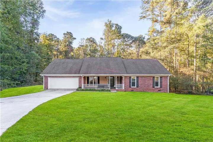 Single story home with a porch, brick siding, a front yard, driveway, and a shingled roof
