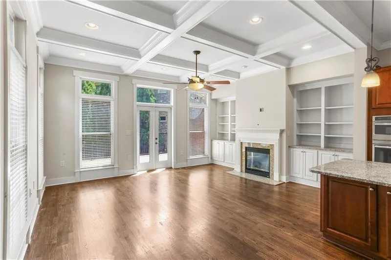 Unfurnished living room featuring french doors, built in features, a premium fireplace, dark wood-style flooring, and beamed ceiling