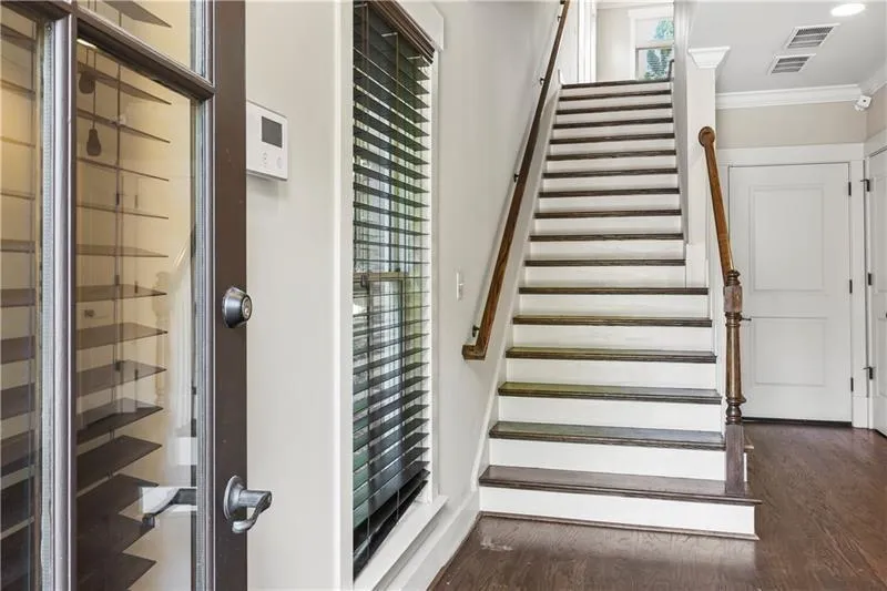 Stairs with crown molding and wood finished floors