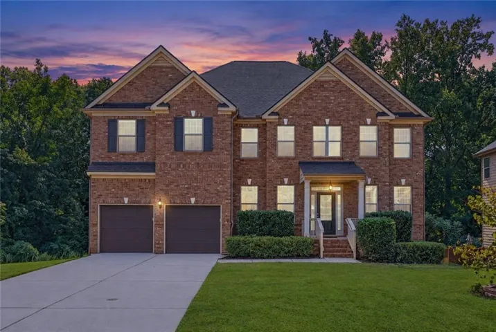Brick exterior with dark shutters, covered entry, and a two-car garage