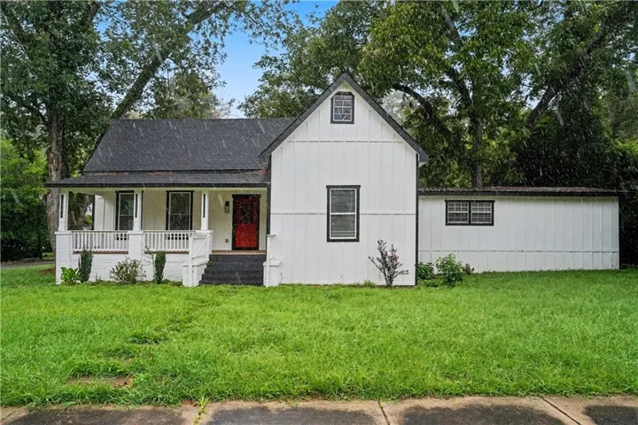 White exterior with black trim accents and a vibrant red entry door