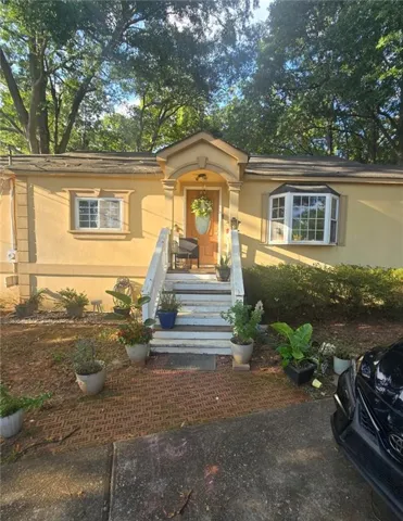 Stucco exterior with a covered entry, wood-finish front door, and a prominent bay window