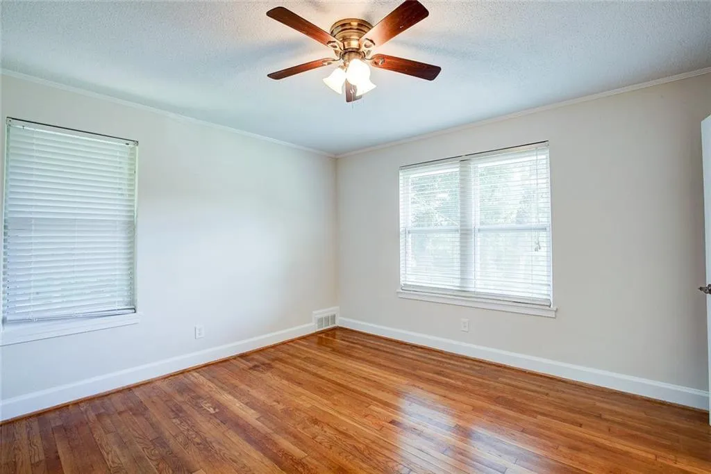Empty room with hardwood / wood-style floors, ceiling fan, a textured ceiling, and crown molding