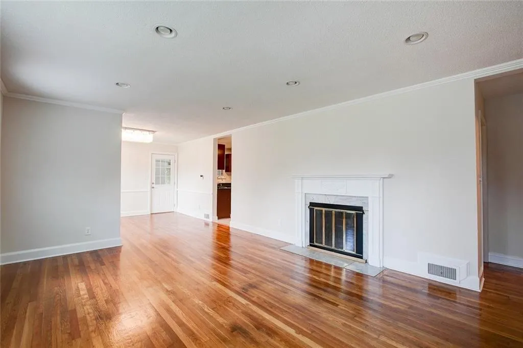 Unfurnished living room featuring crown molding, a fireplace, and hardwood / wood-style floors