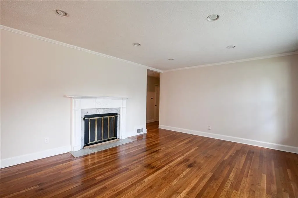 Unfurnished living room with a fireplace, ornamental molding, and hardwood / wood-style floors