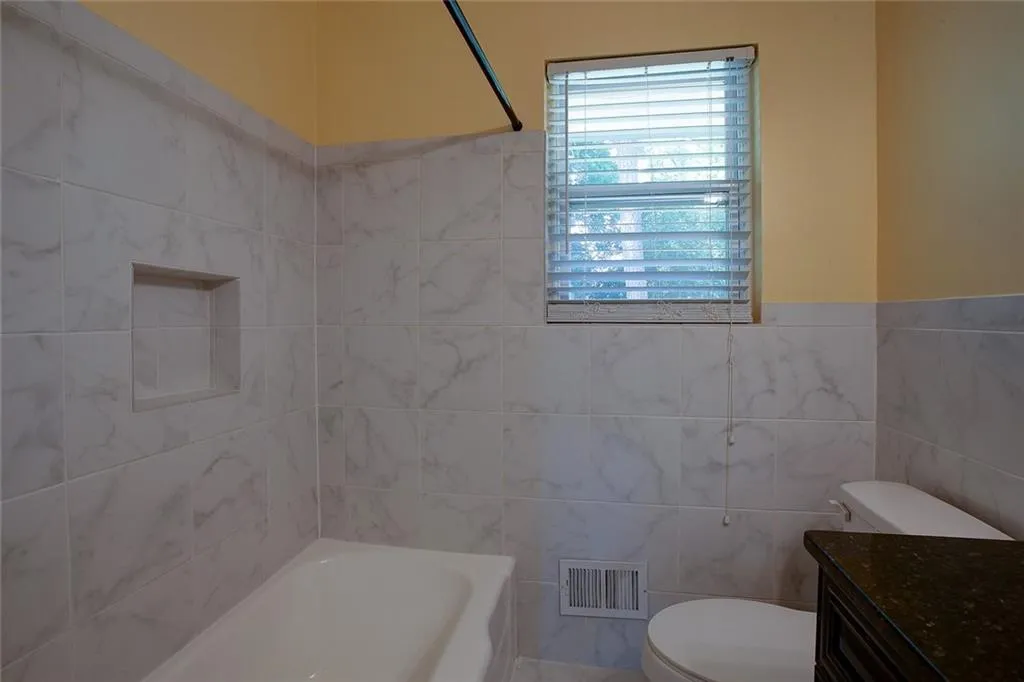 Full bathroom with tile walls, vanity, toilet, and shower / tub combination