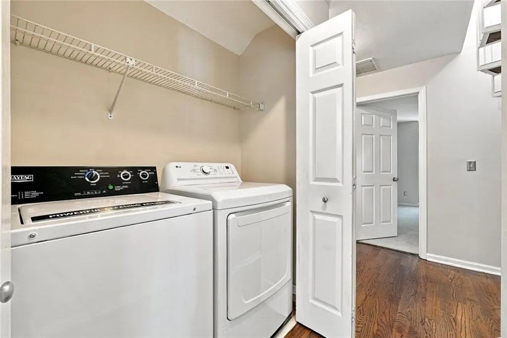 Laundry area featuring wood-finish flooring, a white bi-fold door, and an overhead wire shelving unit
