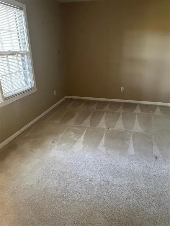 Spare room featuring light colored carpet and baseboards