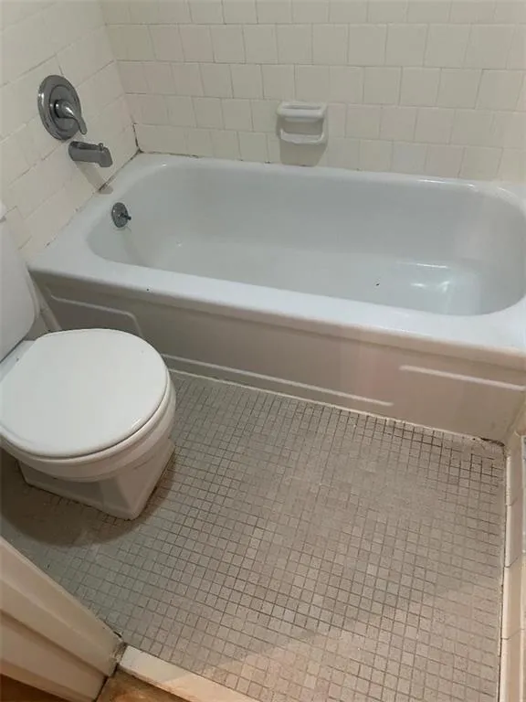 Full bath featuring toilet and tile patterned flooring