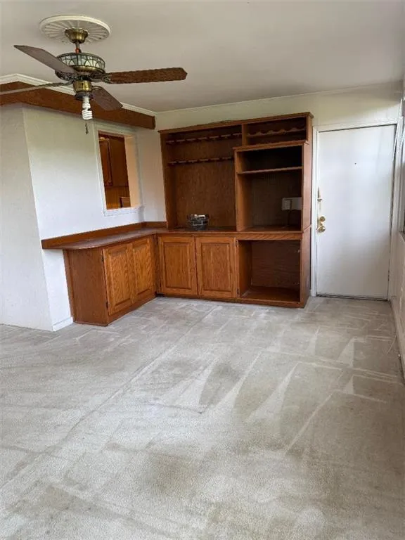Unfurnished living room featuring light colored carpet and ceiling fan