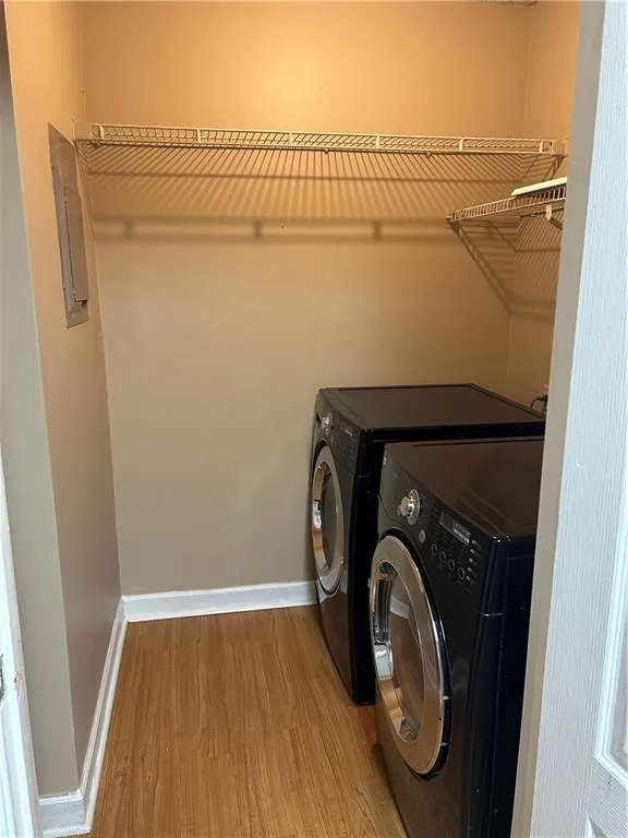 Laundry area featuring light wood-style floors, washer and clothes dryer, and electric panel