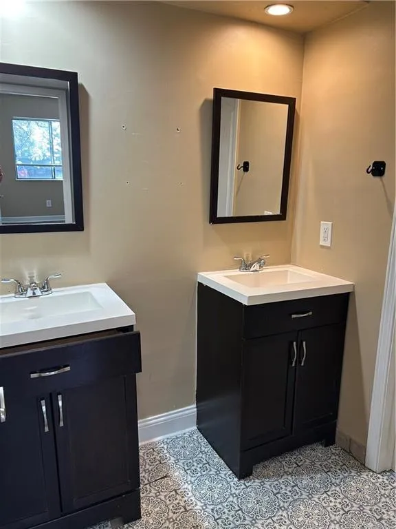Full bath with two vanities and baseboards