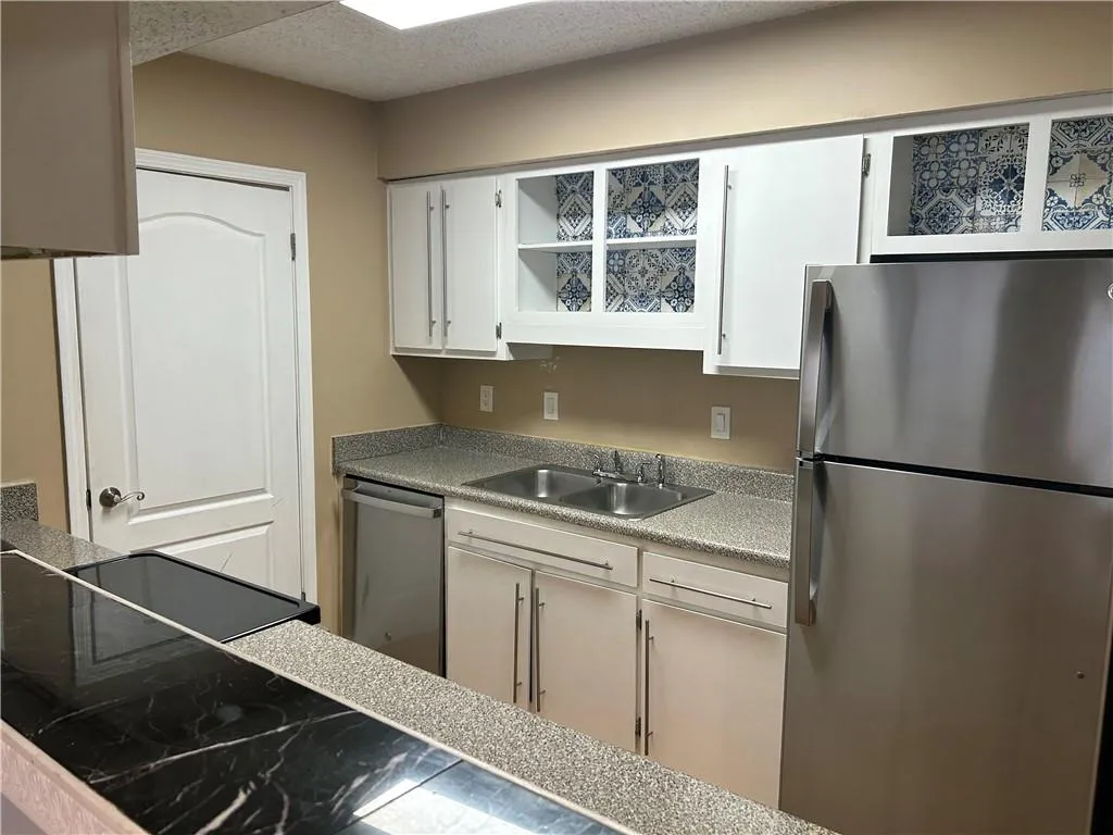 Kitchen with stainless steel appliances, white cabinets, a textured ceiling, and light countertops