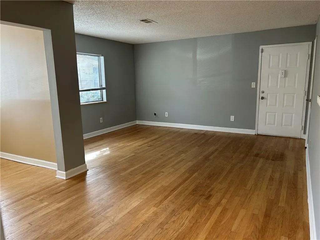 Empty room featuring light wood-type flooring and a textured ceiling