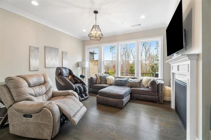 Living room with crown molding, dark wood-type flooring, and a chandelier